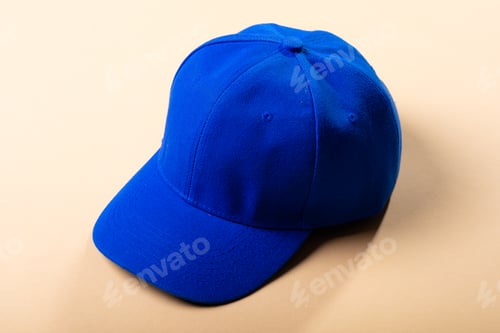 Preview: Composition of traditional peaked blue baseball cap on pale brown background