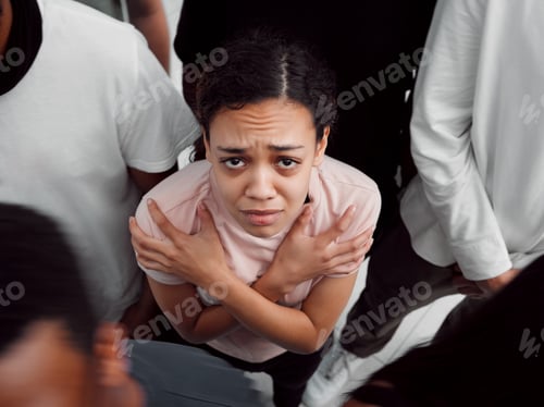 Preview: Shot of a young woman experiencing mental illness while being surrounded by people inside