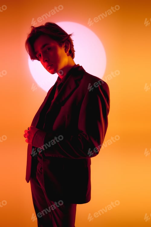 Preview: Stylish young man poses against a vibrant sunset backdrop in a striking silhouette