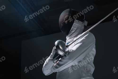 Preview: Low angle view of fencer in fencing mask holding rapier