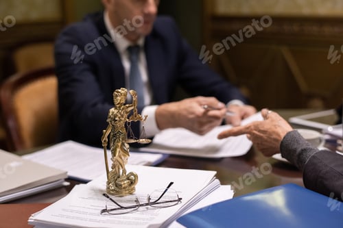 Preview: Statue of justice and eyeglasses on stack of juridical papers