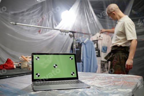 Preview: Open Laptop with Green Mockup Screen Placed on Table in Fashion Artists Studio