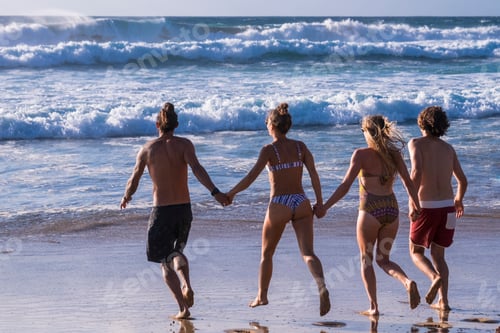 Preview: Back view of group of young people men and women run at the beach to the water