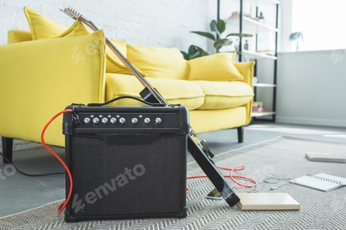 Preview: electric guitar and loud speaker standing on floor with books near sofa