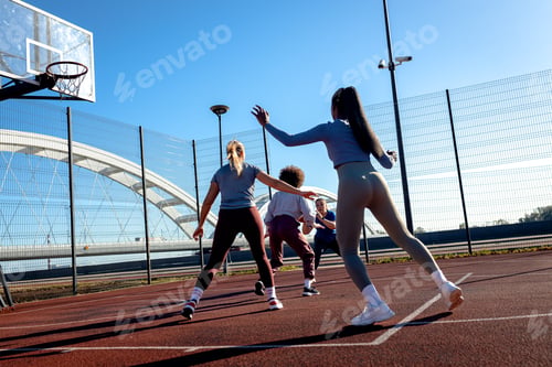 Preview: Diverse group of young woman having fun playing recreational basketball outdoors.