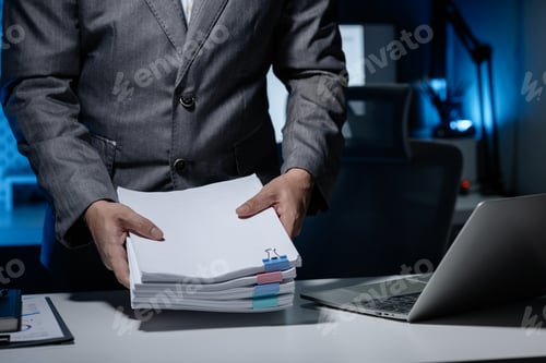 Preview: An employee was tidying up a pile of documents piled on his desk before returning home from work, A