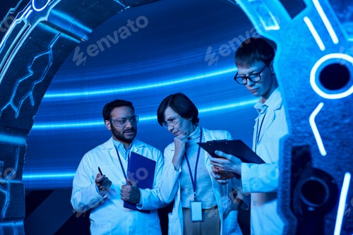 Preview: intern writing on clipboard near new device and multiethnic scientists talking in discovery center