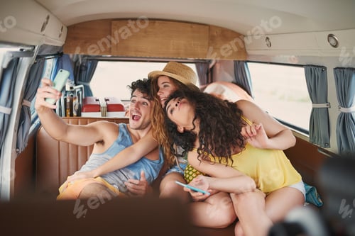 Preview: Shot of a group of young friends taking selfies with a smartphone on a road trip