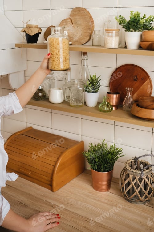 Preview: Close-up of the hostess's hands taking a jar of pasta on a shelf in the kitchen