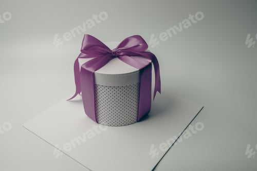 Preview: a small gift box tied with purple ribbon and bow sitting on a paper card