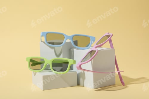 Preview: Colorful sunglasses on white blocks on beige background