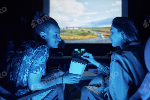 Preview: Young couple watching movie together on big screen in home cinema