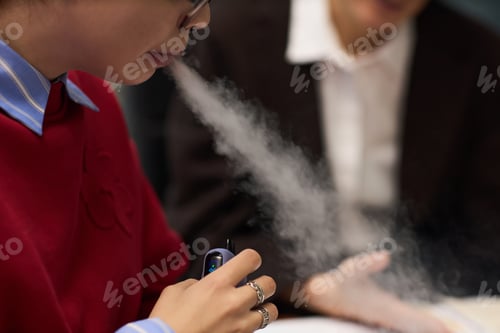Preview: Young Woman Vaping Indoors While Sitting at Office Meeting