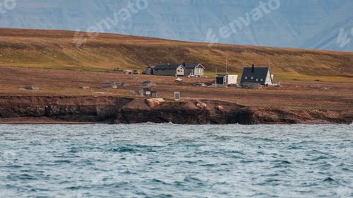 Preview: Remote coastal village in Svalbard with rugged terrain and calm waters under clear sky