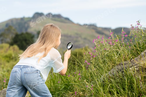 Preview: Cute girl exploring nature with magnifying glass. An inquisitive girl explores nature.