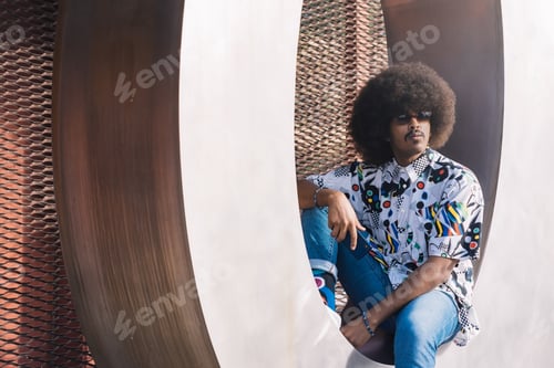 Preview: young boy with afro hair and sunglasses sitting