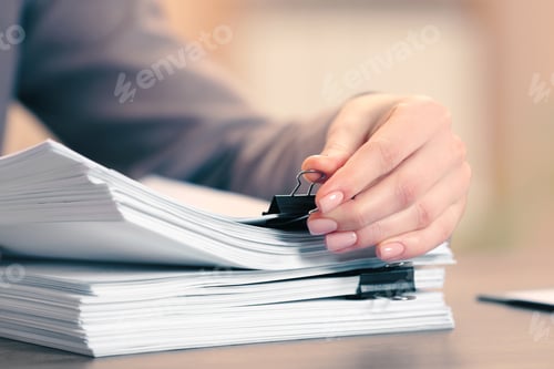 Preview: Woman attaching documents with metal binder clip at table in office, closeup