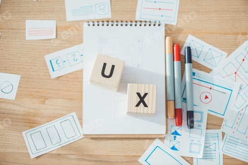 Preview: Top view of cubes with ux letters and website ux app development sketches on wooden table