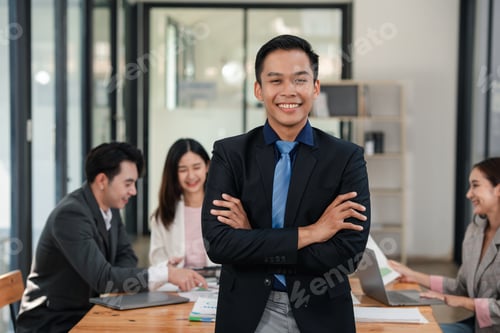 Preview: Confident young businessman with arms crossed standing in office