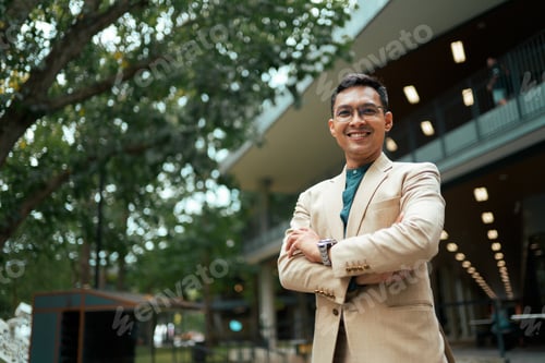 Preview: Professional businessman smiling with arms crossed outdoors