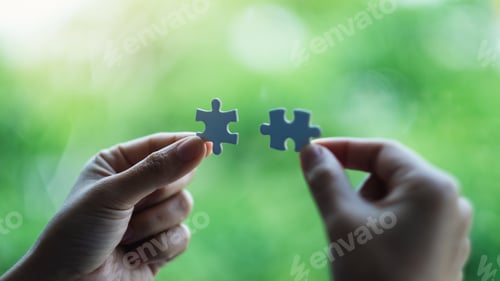 Preview: a woman holding and putting a piece of white jigsaw puzzle together with green nature background