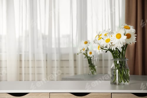 Preview: Vase with beautiful chamomile flowers on cabinet in room. Space for text