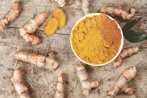 Preview: a bowl of tumericd ginger on top of some root