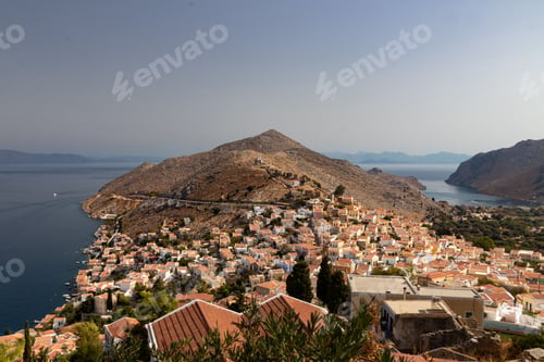 Preview: Scenic view of a small coastal town with residential buildings on a hill in sunlight