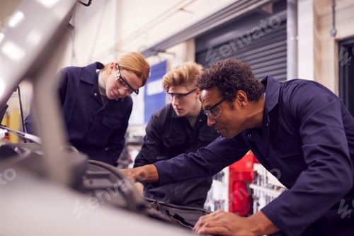 Preview: Male Tutor With Students Looking At Car Engine On Auto Mechanic Apprenticeship Course At College