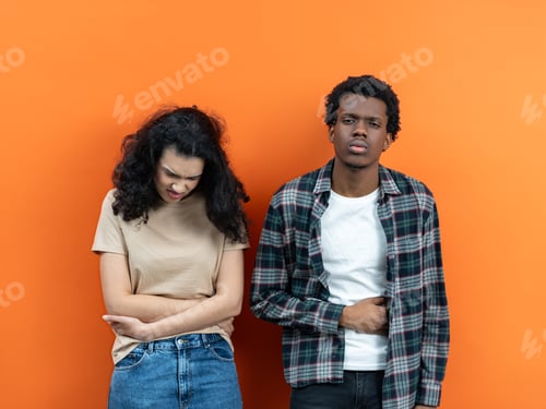 Preview: Young Couple Experiencing Abdominal Pain Together On Orange