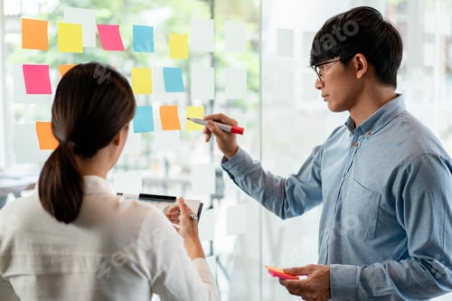 Preview: Two business executive team holding and taking notes keyword on board wall to brainstorm