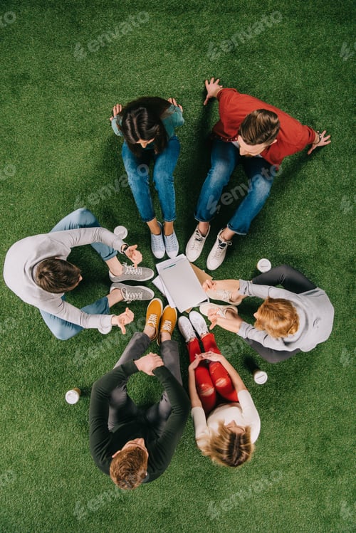 Preview: overhead view of business coworkers having discussion on grass