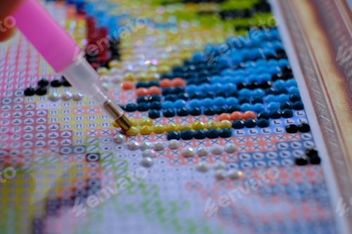 Preview: Diamond painting with pen closeup. art therapy concept. Laying out a diamond mosaic improves a woman