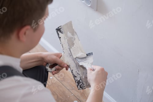 Preview: Man removes holes and bumps on the wall with a spatula and plaster
