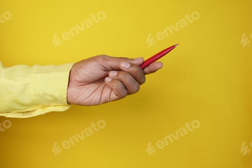 Preview: hand hols a pen against yellow background