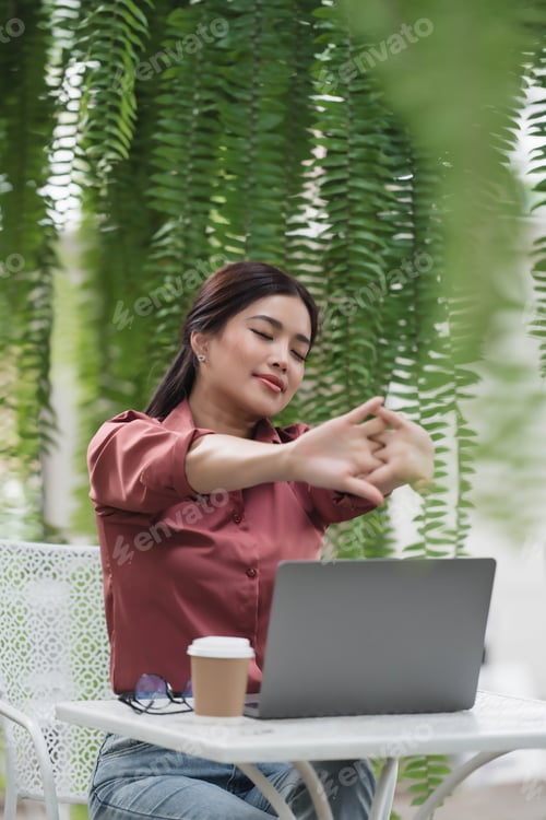 Preview: A woman is sitting at a table with a laptop and a cup of coffee
