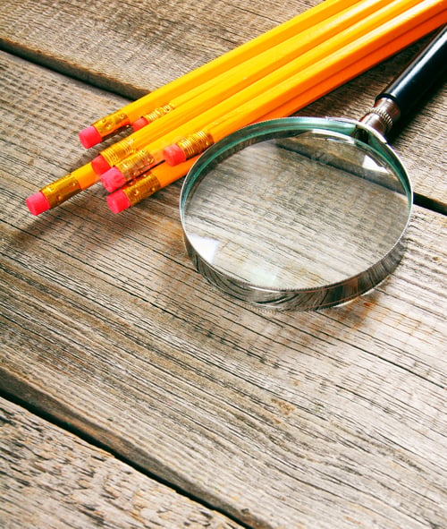 Preview: Magnifier and pencils. On wooden background.