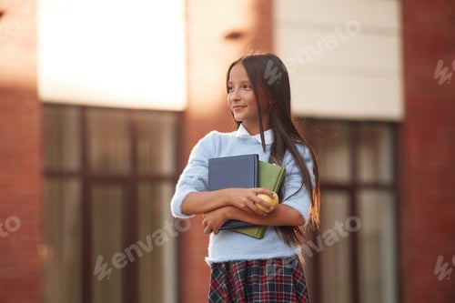 Visualização: Concepção de conhecimento. Menina da escola em uniforme está ao ar livre perto do prédio