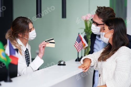 Preview: Adult couple wearing masks checking-in a hotel
