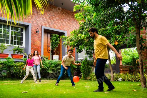 Preview: Indian parents and kids laugh and play ball game Piggy in the Middle in backyard garden