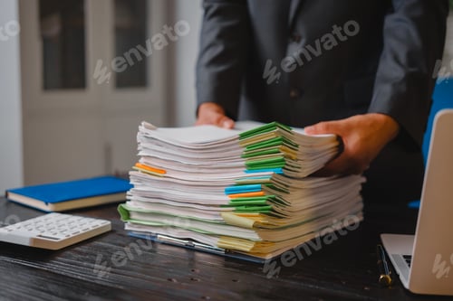 Preview: A businessman sits at his desk, working late into night on his laptop.reviews documents carefully
