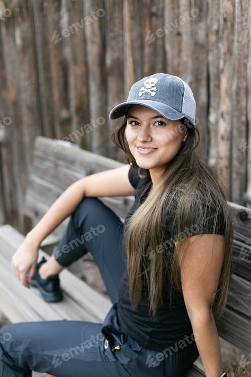 Preview: Portrait of young woman looking at the camera sitting in a wooden bench