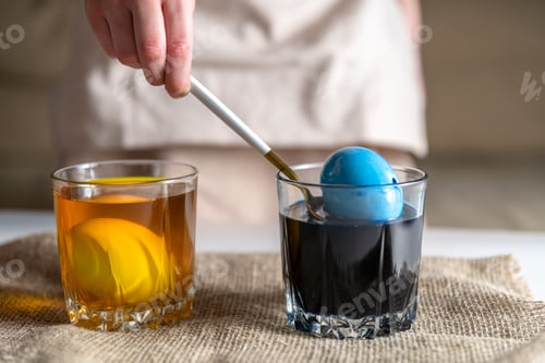 Preview: girl at home in the kitchen dyes eggs for Easter