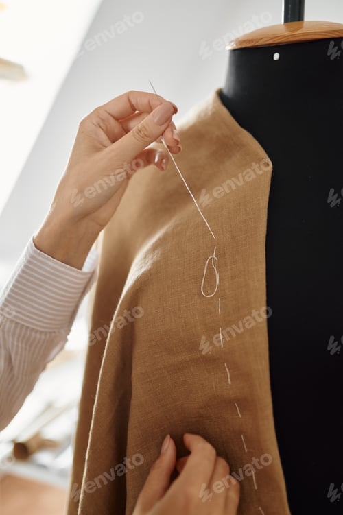 Preview: Seamstress hemming dress on mannequin, workshop