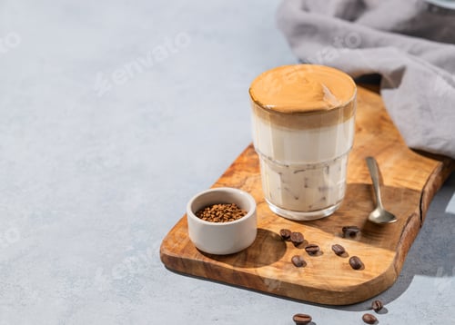 Preview: Dalgona coffee. Whipped instant coffee in a glass on a wooden board with coffee beans