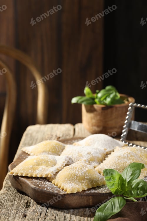 Preview: Uncooked ravioli and basil on wooden table. Space for text