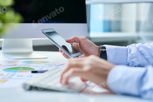Preview: Crop entrepreneur with smartphone at workplace