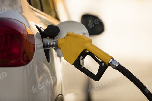 Preview: White car at a gas station being filled with fuel