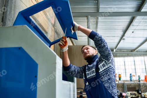 Preview: Man Fixing Machine Units at Factory