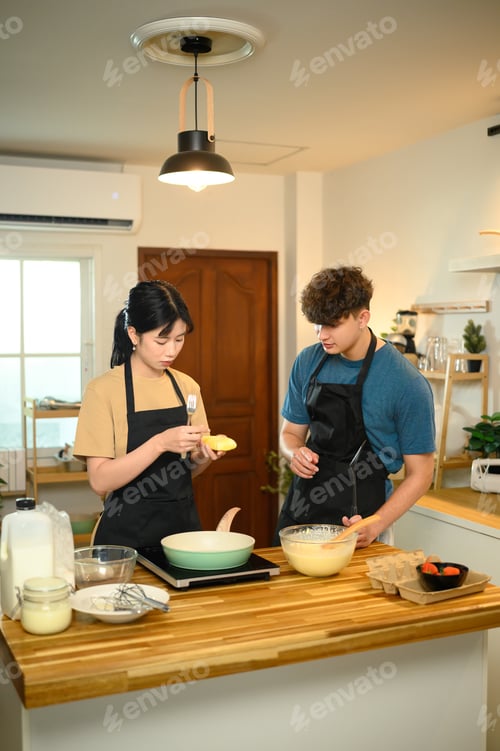 Preview: Couple enjoying morning cooking time, preparing pancake batter together in kitchen